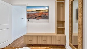 Una camera da letto con un letto, una panca di legno, una TV a parete e un grande specchio.