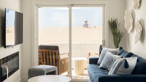 Ein Wohnzimmer mit Fernseher, einer Couch, einem Tisch und Blick auf den Strand.