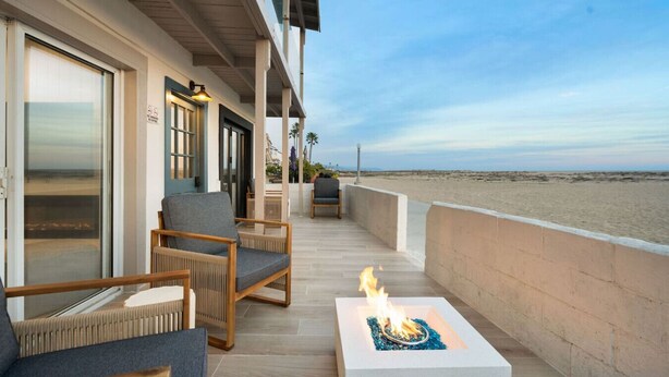 Ein Balkon mit Sitzgelegenheit im Freien, einer Feuerstelle und Blick auf den Strand.