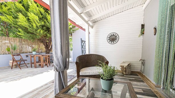 A covered patio with a glass table, wicker chair, and potted plant. - Sunlight  Maisonette by RentalsPro (Nikiti)