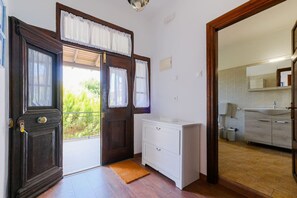 Una habitación con puerta de madera, un armario blanco y vistas a un balcón.