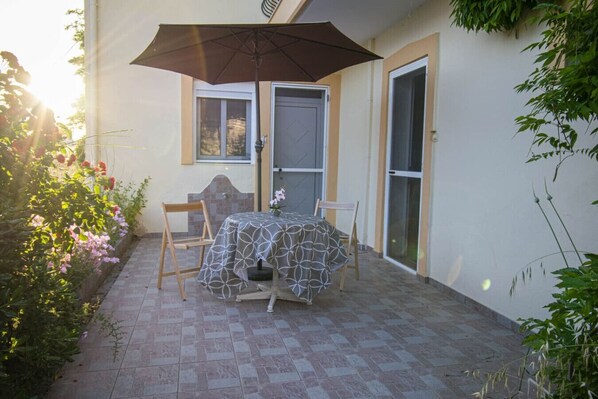A patio with a table and chairs, a large umbrella, and a door.