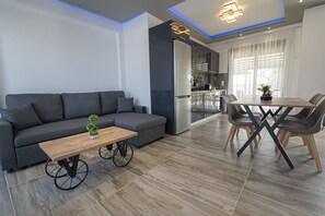 Een moderne woonkamer met een bank, salontafel en een eethoek.