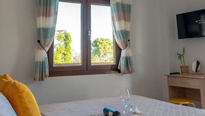 A bedroom with a bed, curtains, a TV, a desk, and a window. - Dimi Seafront Αpartment by Rentals Pro (Nea Moudania)