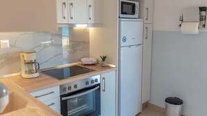 A modern kitchen with white cabinets, a microwave, a coffee maker, and an oven. - Dimi Seafront Αpartment by Rentals Pro (Nea Moudania)