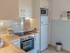 Eine moderne Küche mit weißen Schränken, einer Mikrowelle, einer Kaffeemaschine und einem Backofen.