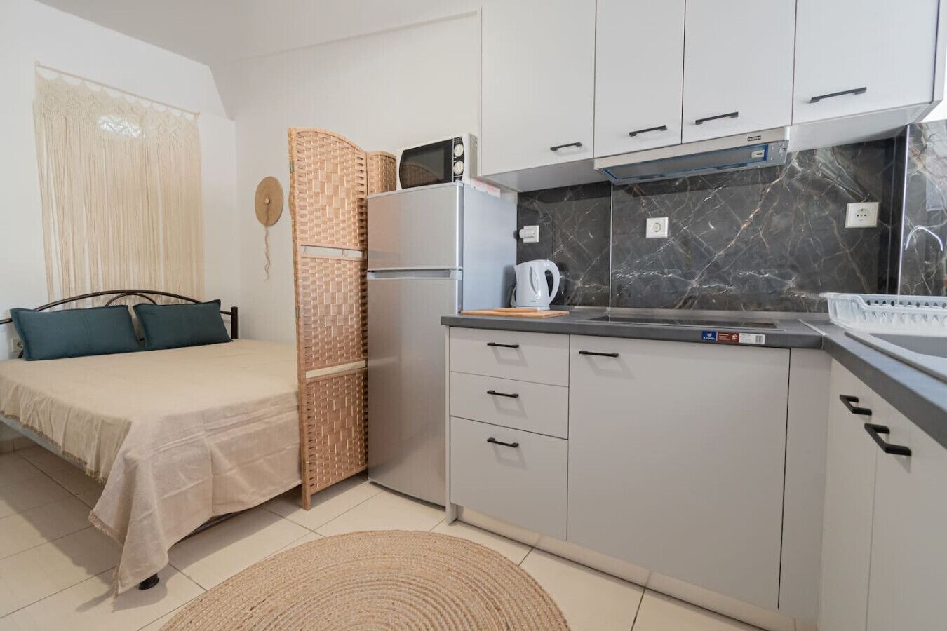 Habitación de hotel compacta con cama, kitchenette y vistas al exterior.