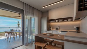 Une cuisine moderne avec un coin repas, de grandes fenêtres et une vue sur la mer.