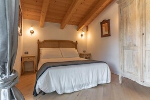Ein Schlafzimmer mit Holzboden, einem Bett mit weißer Bettwäsche, zwei Nachttischen und einem Kleiderschrank.