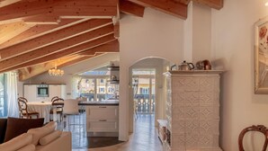 A spacious loft with a high ceiling, wooden beams, a dining area, a kitchen, and a view of the outside. - Apartment 'Alpine Nest Loft' with Mountain View, Shared Pool and Wi-Fi (Pieve di Ledro)