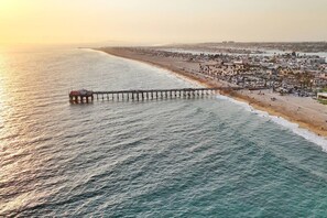 A pier extending into the ocean with a beach and cityscape in the background. - Remodeled 2-Bedroom Suite in Beachfront Building (Newport Beach)
