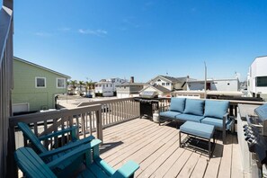 A deck with outdoor seating, a barbecue grill, and a view of neighboring houses.