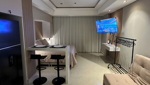 A modern hotel room with a bed, a dining area, a TV, and a seating area. - The Suite Thirteen is a modern, minimalist apartment suite for short-term stays (Cartagena de Indias)