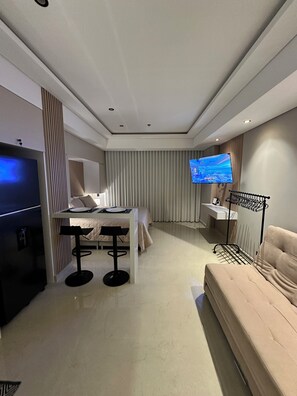 A modern hotel room with a bed, a dining area, a TV, and a seating area. - The Suite Thirteen is a modern, minimalist apartment suite for short-term stays (Cartagena de Indias)