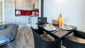 Une cuisine moderne avec des meubles gris, un pare-feu rouge et un coin repas avec une table dressée pour deux personnes.