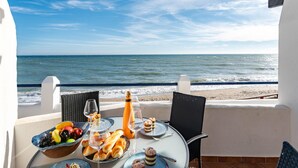 Une table dressée avec de la nourriture et des boissons sur un balcon donnant sur la mer.