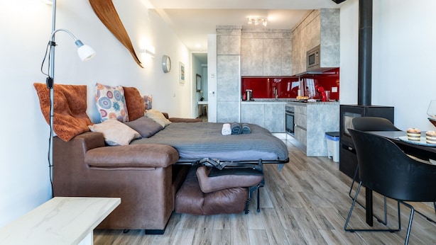 Une chambre moderne équipée d’un canapé-lit, d’un bureau, d’une chaise, d’un ventilateur de plafond et d’un coin cuisine.