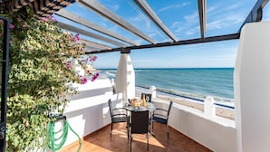 Un balcon avec vue sur la mer, une table avec des chaises et un jardin suspendu.