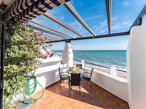 Ein Balkon mit Meerblick, einem Tisch mit Stühlen und einem hängenden Garten.