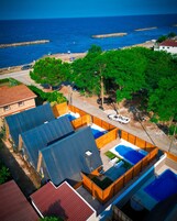 Zona residencial con una gran piscina, un espacio exterior cubierto y vistas al mar.