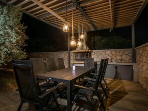 Eine Terrasse im Freien mit Tisch, Stühlen, einer Steinmauer und einem Grill.