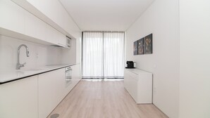 Cucina moderna con mobili bianchi, un rubinetto in acciaio inossidabile e una finestra con tende trasparenti.