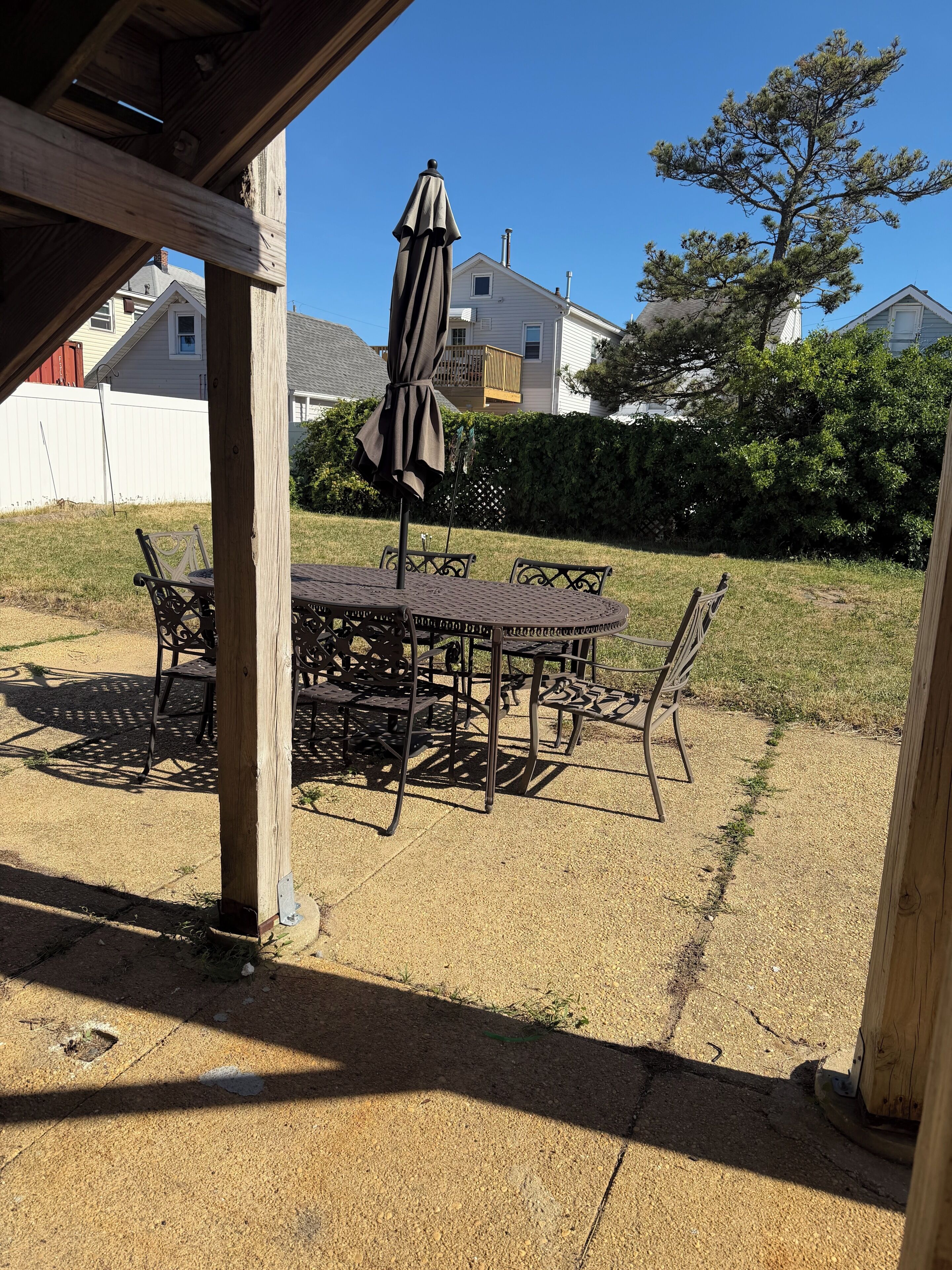 Une terrasse avec une table et des chaises, une pergola en bois et une vue sur des maisons et des arbres.
