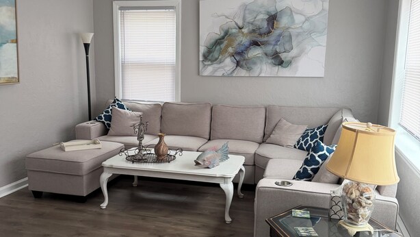 Ein Wohnzimmer mit Sofa, Hocker, Couchtisch, Lampe und Kunstwerken.