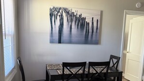 Ein Essbereich mit Tisch und Stühlen, einem Bild an der Wand und einer Tür.