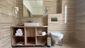Un bagno moderno con una parete in marmo, un mobiletto in legno, un water e uno specchio.