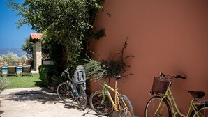 Una bicicleta apoyada en una pared, una silla y una mesita en un espacio al aire libre y soleado.