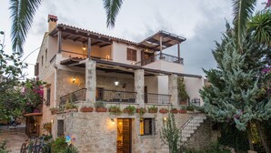 Un edificio de piedra de dos pisos con balcones, una escalera y plantas en macetas.