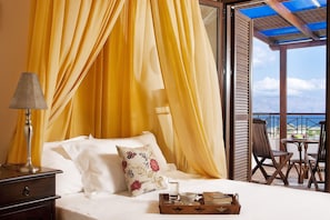 A bed with yellow curtains, a bedside lamp, and a tray with a glass of water and a book. - Crete Villa in Mediterranean Sea (Kissamos)