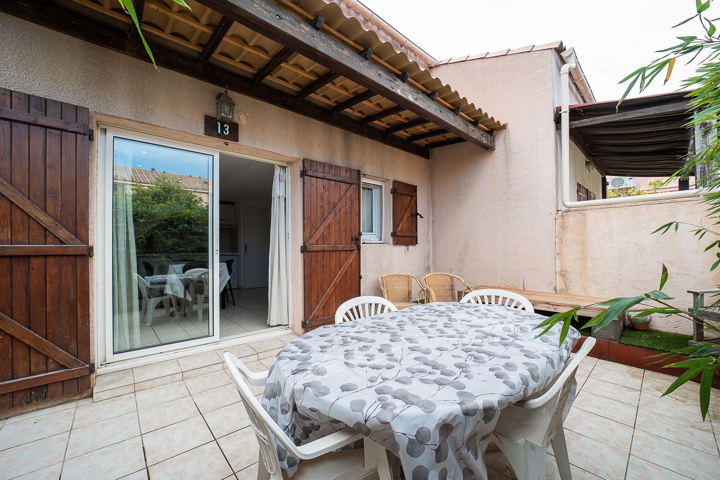 A patio with a table and chairs, a sliding glass door, and a wooden door.