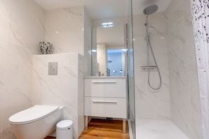 Une salle de bain moderne équipée de toilettes, d’une douche et d’un meuble-lavabo avec des tiroirs.