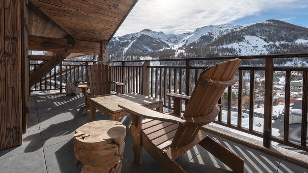 A wooden deck with a table and chairs, overlooking a snowy mountain landscape. - Le Panorama du Puy - Dans la station d'Auron (Saint-Étienne-de-Tinée)