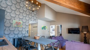 A modern living room with a dining area, wooden ceiling beams, and a patterned wall. - Le Panorama du Puy - Dans la station d'Auron (Saint-Étienne-de-Tinée)