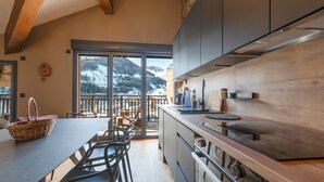 A modern kitchen with a large island, wooden beams, and a view of snow-capped mountains. - Le Panorama du Puy - Dans la station d'Auron (Saint-Étienne-de-Tinée)
