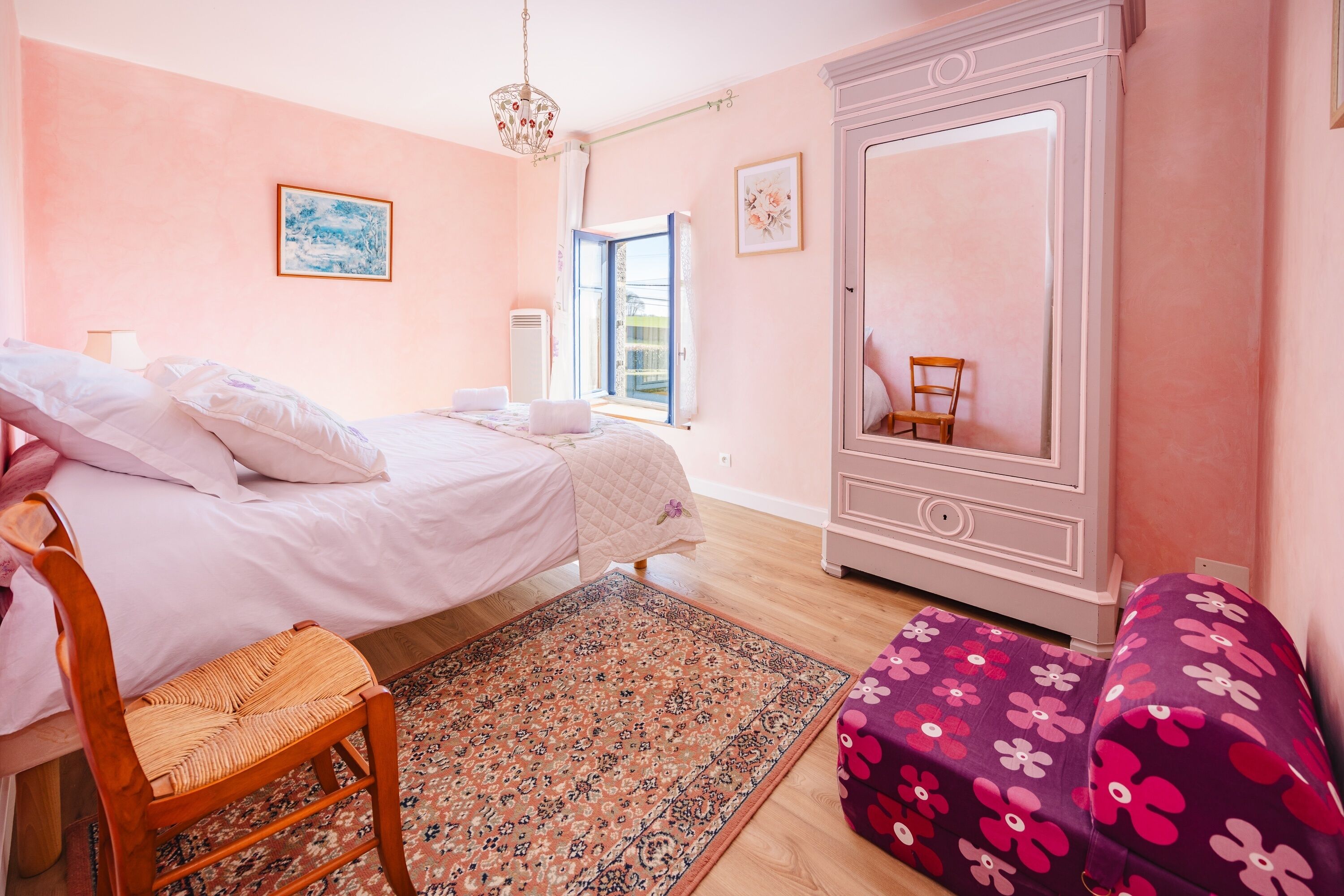 Une chambre à coucher avec un lit, une chaise, une commode et une fenêtre.