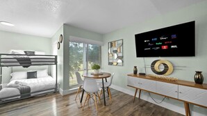 Une chambre moderne équipée d’un lit superposé, d’un coin repas avec une table ronde et d’un téléviseur permettant d’accéder à différents services de diffusion en continu.