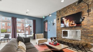 Un salon moderne avec un mur en pierre, un téléviseur à écran plat et une cheminée.