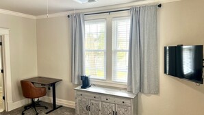 A room with a desk, chair, window with curtains, ceiling fan, and a mounted TV. - Rustic Elegance Steps from Bourbon Country (Versailles)