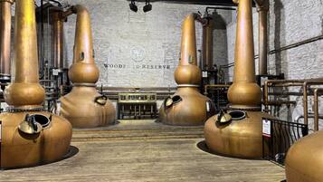 Une distillerie dotée de grandes cuves de distillation en cuivre et d’un plancher en bois.