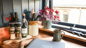 A kitchen counter with cooking essentials, a notebook, and a view of the street outside. - Dunfell Shepherd's Hut (Appleby-in-Westmorland)