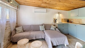 Una habitación acogedora con techo de madera, una cama, una mesita redonda y una kitchenette.