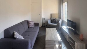 Ein modernes Wohnzimmer mit einer Couch, einem Couchtisch, einem Fernseher und einer Lampe.