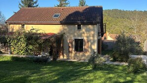 A house with a tiled roof, a small window with shutters, and a grassy yard. - Chez Fabrice* Maison avec piscine chauffée (Daglan)