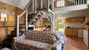 A spacious living area with a sofa, a dining table, a staircase, and a kitchen in the background. - Domaine*Charme*Piscine*Domme (Domme)