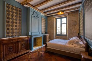 Una camera da letto con un letto, un camino, una finestra e travi in legno al soffitto.