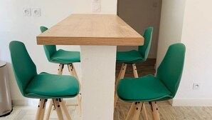 Een moderne eetruimte met een houten tafel en groene fauteuils.
